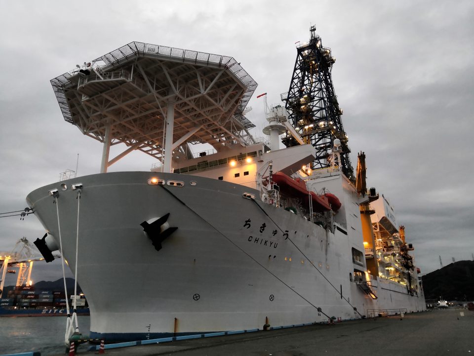 A large white ship moored in a dock, taken from the bow.